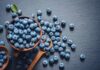 A bowl of fresh blueberries on a dark surface