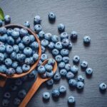 A bowl of fresh blueberries on a dark surface