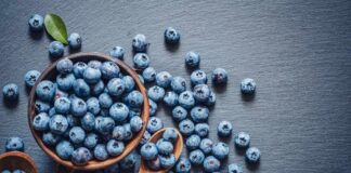A bowl of fresh blueberries on a dark surface
