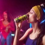 Woman in sportswear drinking an energy drink at a vibrant fitness party