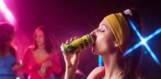 Woman in sportswear drinking an energy drink at a vibrant fitness party