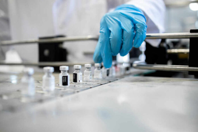 shutterstock2116117133jpg A healthcare professional in a lab preparing vaccine vials