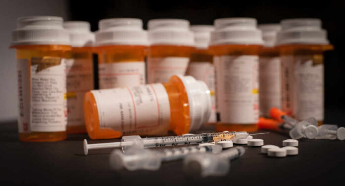 shutterstock_1138870511.jpg Various prescription medication bottles and syringes on a table