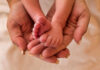 A close-up of a babys feet being held gently in adult hands