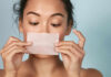 Woman holding a skincare strip in front of her face