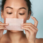 Woman holding a skincare strip in front of her face