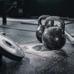 Kettlebells and weights on a gym floor with chalk dust