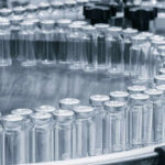 Close-up of glass vials arranged in a circular conveyor system in a pharmaceutical setting