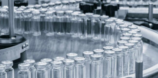 Close-up of glass vials arranged in a circular conveyor system in a pharmaceutical setting