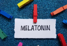 A piece of paper with the word MELATONIN clipped by a red clothespin, surrounded by colorful clothespins on a blue glitter background