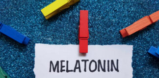 A piece of paper with the word MELATONIN clipped by a red clothespin, surrounded by colorful clothespins on a blue glitter background