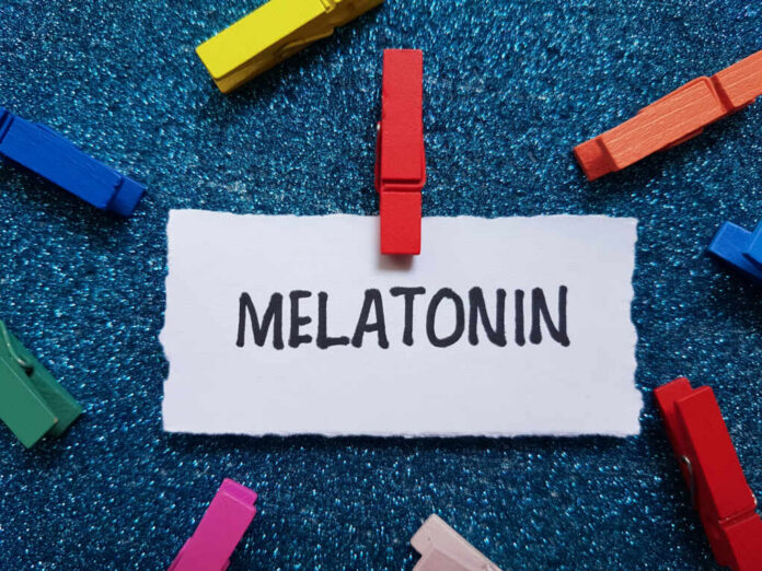 A piece of paper with the word MELATONIN clipped by a red clothespin, surrounded by colorful clothespins on a blue glitter background