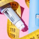 An insulin pen and measuring tape on a pink background