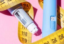 An insulin pen and measuring tape on a pink background
