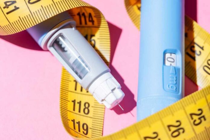 shutterstock_2650279637.jpg An insulin pen and measuring tape on a pink background