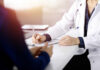 A doctor writing notes during a consultation with a patient