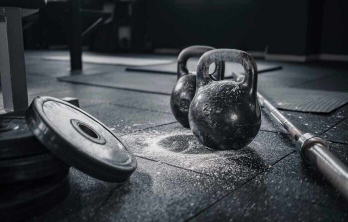 Kettlebells and weights on a gym floor with chalk dust
