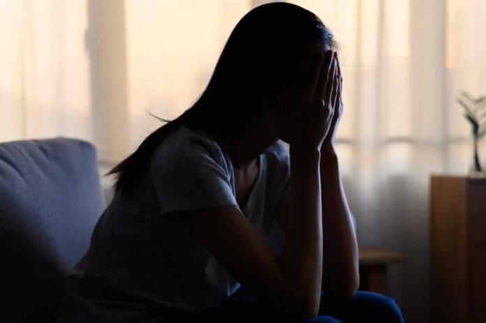 A silhouette of a person sitting with their head in their hands, conveying distress