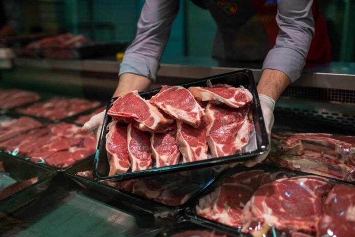 A butcher holding a tray of fresh meat cuts