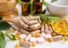 Various herbal supplements and vitamins arranged with leaves and a mortar