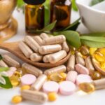Various herbal supplements and vitamins arranged with leaves and a mortar