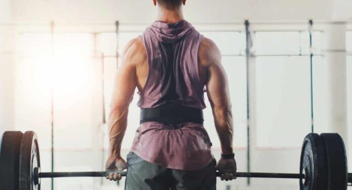 A muscular person preparing to lift a barbell in a gym setting