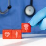 The Startling Power of Optimism on Health A doctor's gloved hand placing red blocks with health symbols on a table