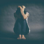 The Unexpected Antidote to Loneliness A person sitting on the floor with their arms wrapped around their knees, conveying a sense of distress