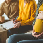 Maternal Immunity Twist: The Male Fetus Factor Pregnant woman sitting with two people discussing notes in a cozy living room