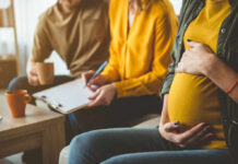 Maternal Immunity Twist: The Male Fetus Factor Pregnant woman sitting with two people discussing notes in a cozy living room