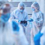 Healthcare professionals in protective gear discussing on a tablet