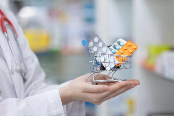 Woman,Pharmacists,Holding,Shopping,Trolley,With,Set,Medicine,In,Drug A doctor holding a miniature shopping cart filled with various medication packs