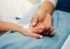 Antibody Discovery Rewrites MS Diagnoses A patient holding hands with a loved one in a hospital setting