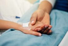 Antibody Discovery Rewrites MS Diagnoses A patient holding hands with a loved one in a hospital setting