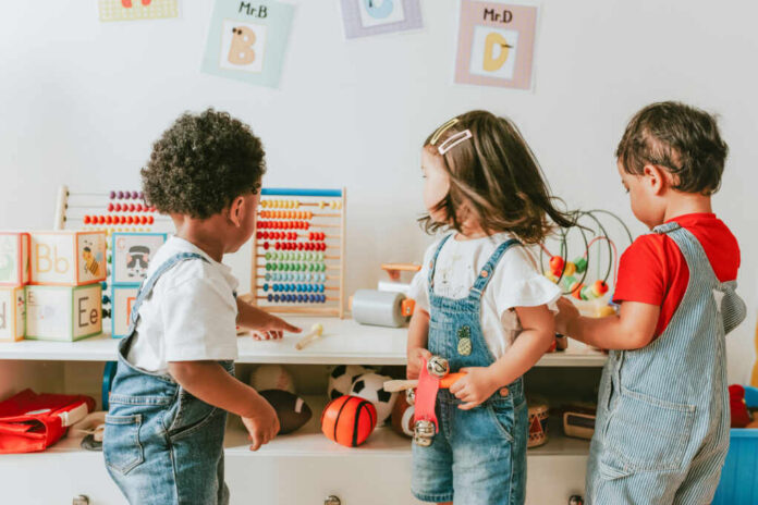 Three children engaged in play with educational toys in a colorful classroom