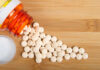 Effect of Pain Pills on Your Heart Health After 60 Spilled white pills from a prescription bottle on a wooden surface