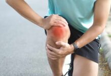 How To Ease Post-Workout Muscle Soreness Athlete holding their knee in pain while exercising outdoors