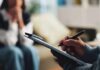 America’s Midlife Epidemic—Worse Than Europe? A therapist taking notes during a session with a client in the background