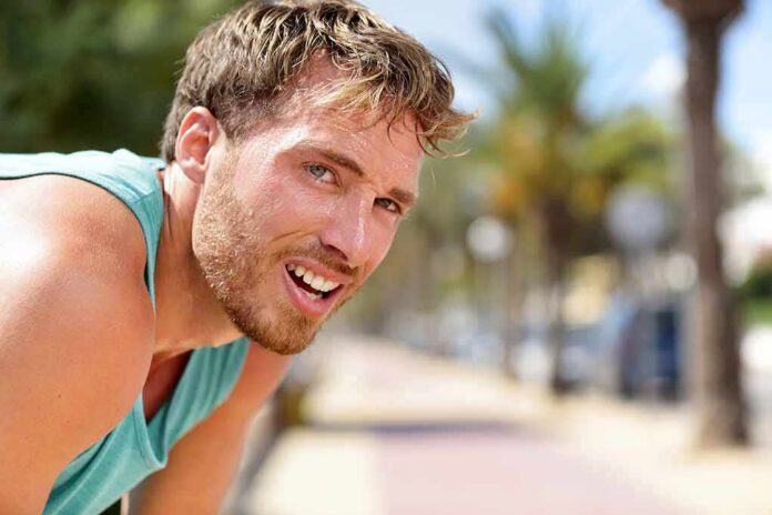 man in athletic tank top resting outdoors