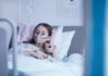 Radiation Roulette: Genes That Decide Who Gets Cancer Child in hospital bed with oxygen mask holding teddy bear