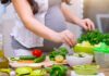 Person preparing a fresh salad with green vegetables in a kitchen