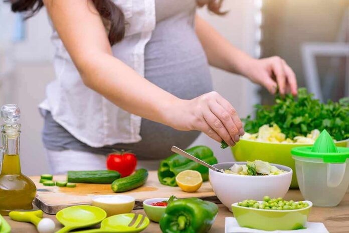 Person preparing a fresh salad with green vegetables in a kitchen