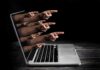 How Algorithms Are Quietly Breeding ‘Stupidity’ Laptop with multiple hands pointing from the screen