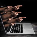 Laptop with multiple hands pointing from the screen