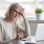 Older woman with glasses looking concerned at laptop
