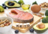 Forgotten Nutrient, Loud Immune Impact A variety of healthy foods arranged on a table, including salmon, avocado, and nuts, with wooden blocks spelling 'KETO'.