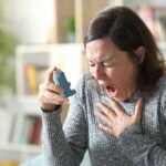 Woman holding an inhaler during a coughing fit