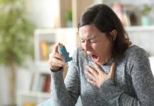Woman holding an inhaler during a coughing fit
