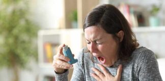 Woman holding an inhaler during a coughing fit