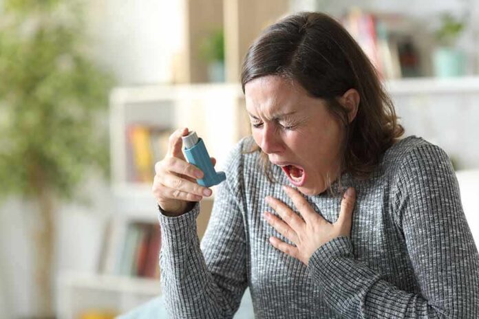 Woman holding an inhaler during a coughing fit
